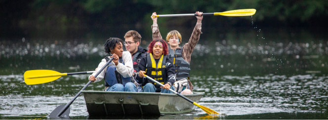 happy students paddling in boat